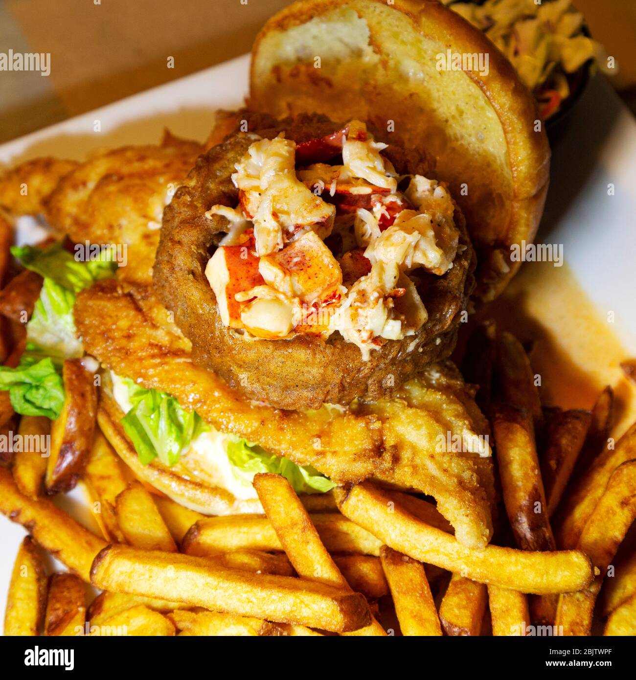Fried haddock served with lobster meat, French fries and a bread bun in Barrington, Nova Scotia, Canada. Stock Photo