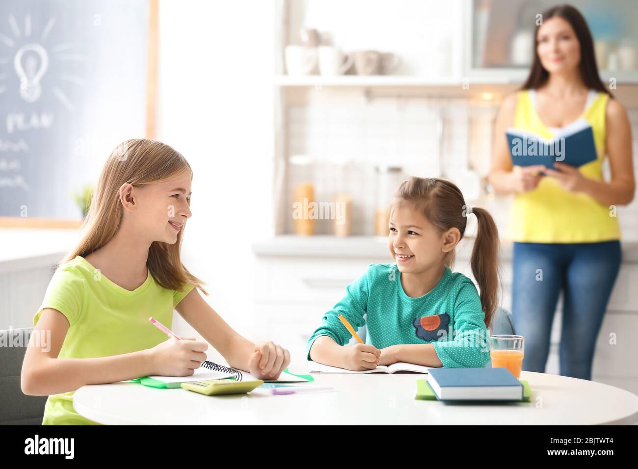 Cute little sisters doing homework in kitchen Stock Photo - Alamy