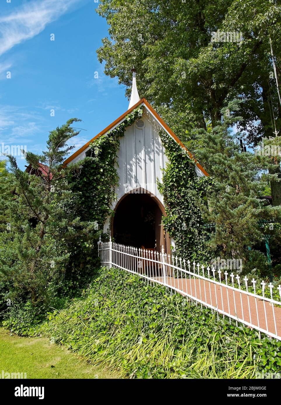 tiny chapel, arched entrance door, ivy climbing walls, white iron picket fence, path, green vegetation, doors open, wedding venue, USA, KY, Kentucky; Stock Photo