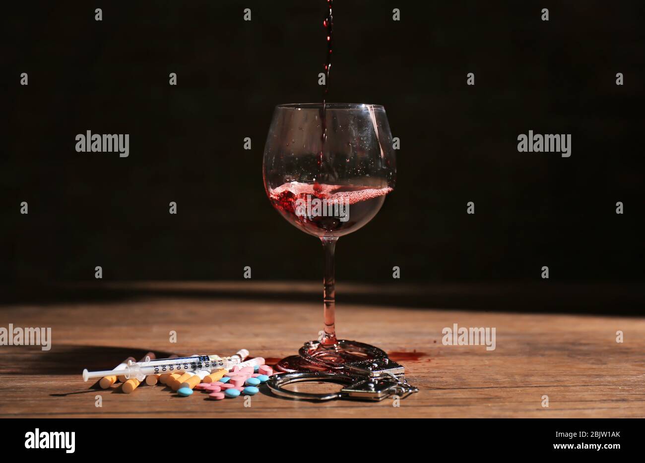 Composition with wine, drugs and handcuffs on table. Alcoholism and