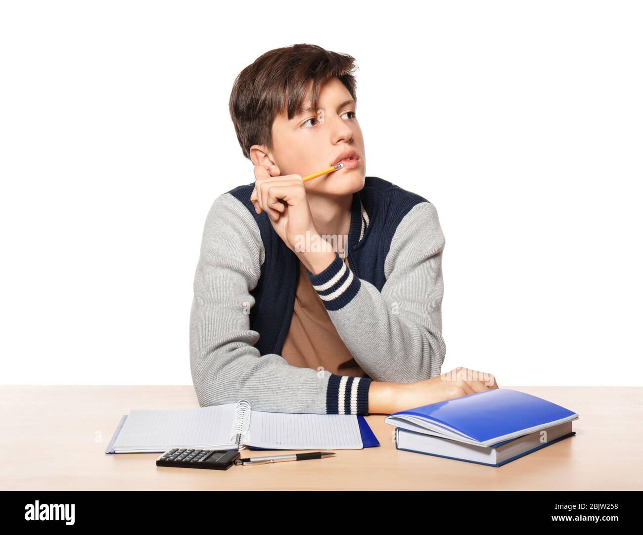 Cute teenager boy doing homework against white background Stock Photo ...