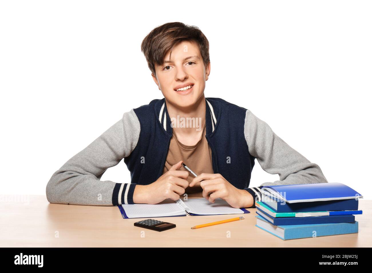 Cute teenager boy doing homework against white background Stock Photo ...