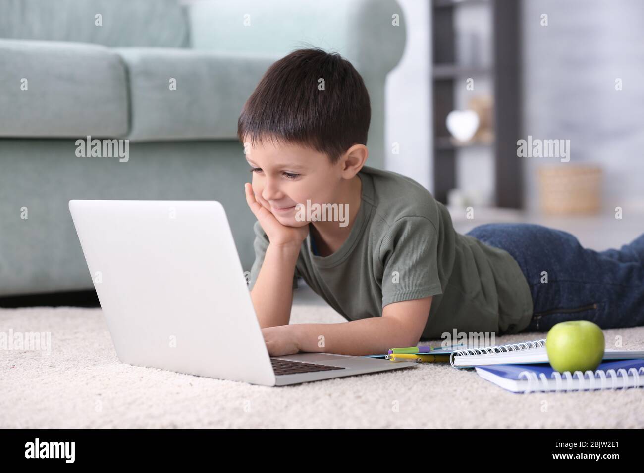 Cute little boy using laptop while doing homework indoors Stock Photo ...
