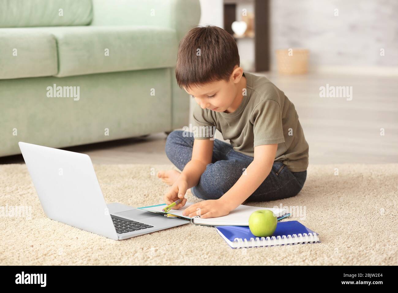 Cute little boy using laptop while doing homework indoors Stock Photo ...