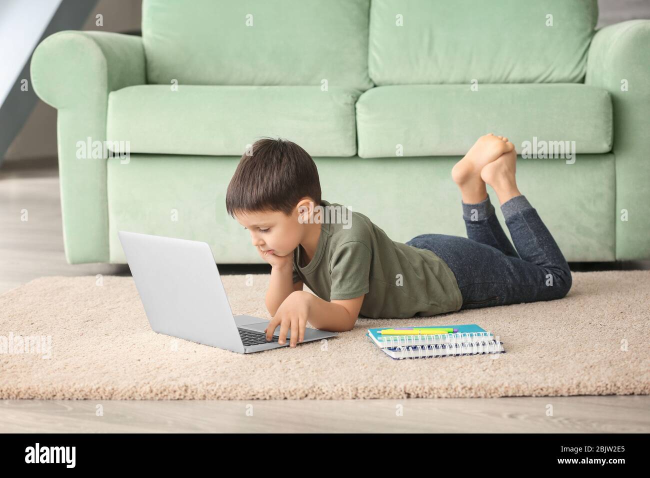 Cute little boy using laptop while doing homework indoors Stock Photo ...