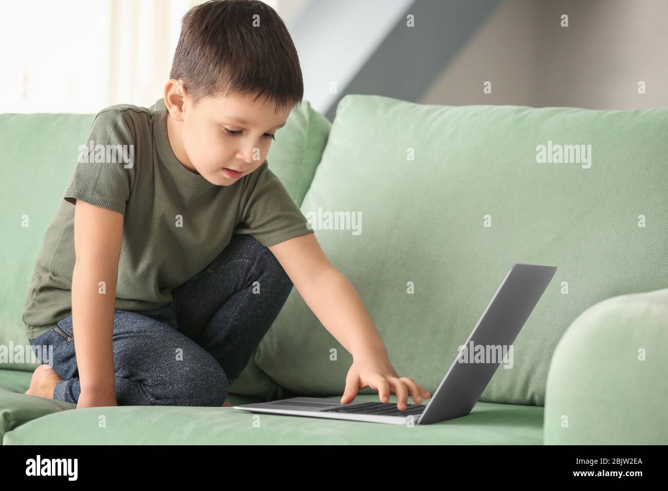 Cute little boy using laptop while doing homework indoors Stock Photo ...