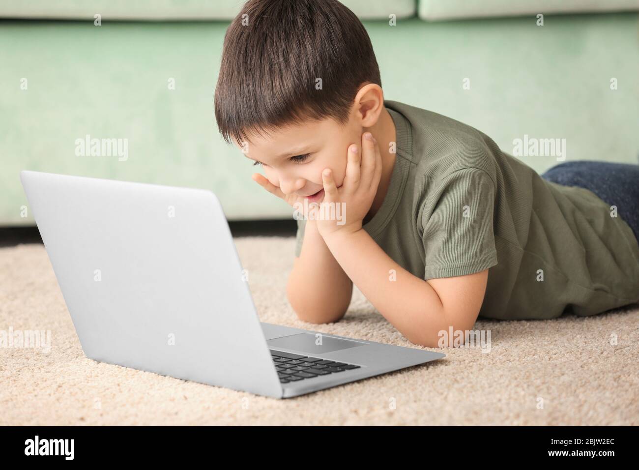 Cute little boy using laptop while doing homework indoors Stock Photo ...