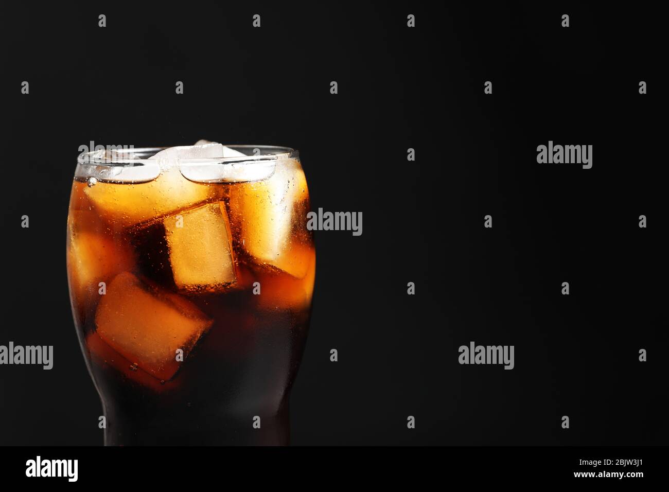 Glass of refreshing cola with ice on black background, closeup Stock ...