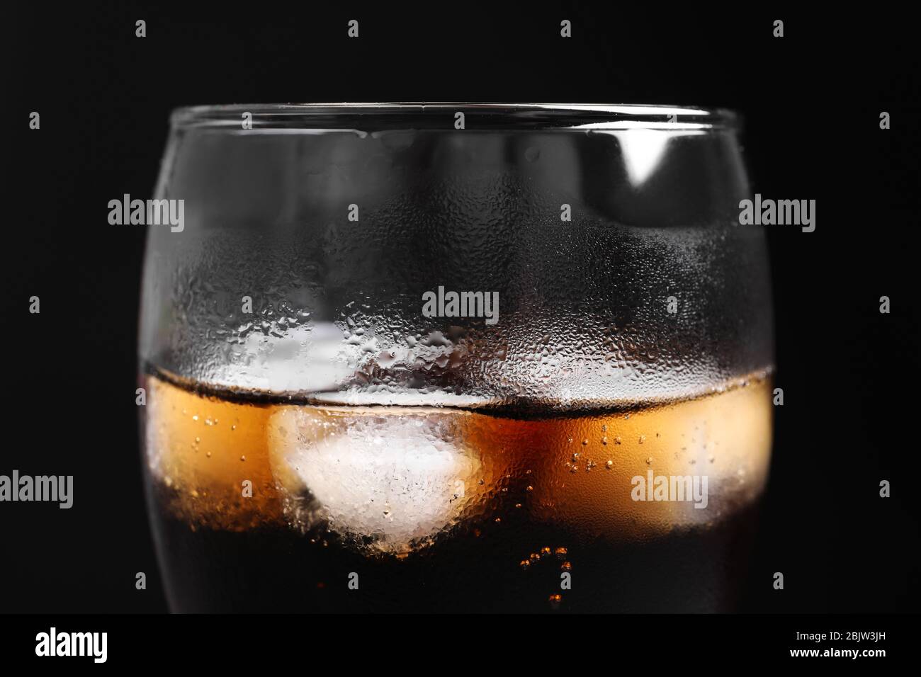 Glass of refreshing cola with ice on black background, closeup Stock ...
