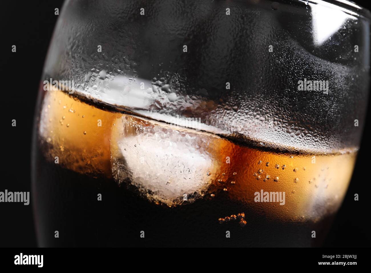 Glass of refreshing cola with ice on black background, closeup Stock ...