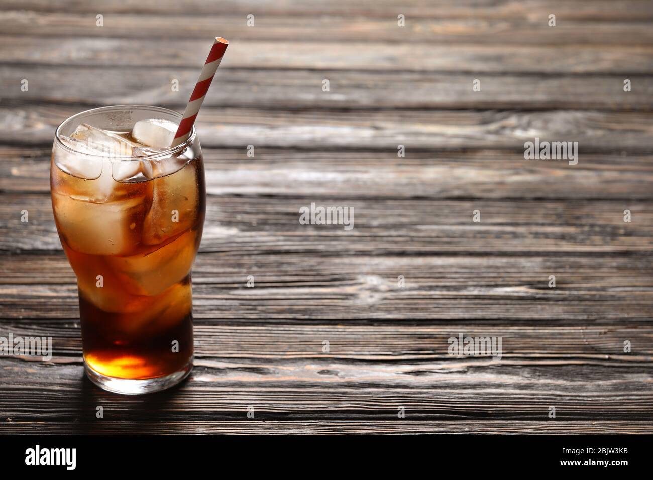 Glass of refreshing cola with ice on wooden background Stock Photo - Alamy