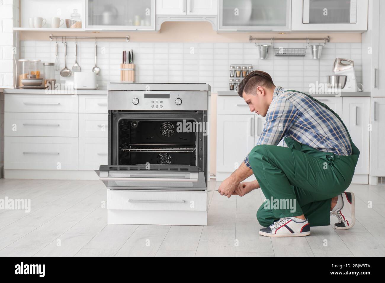 Young man repairing oven in kitchen Stock Photo