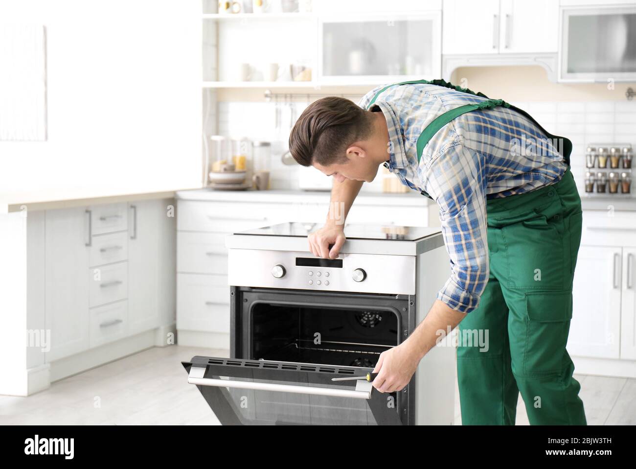 Young man repairing oven in kitchen Stock Photo
