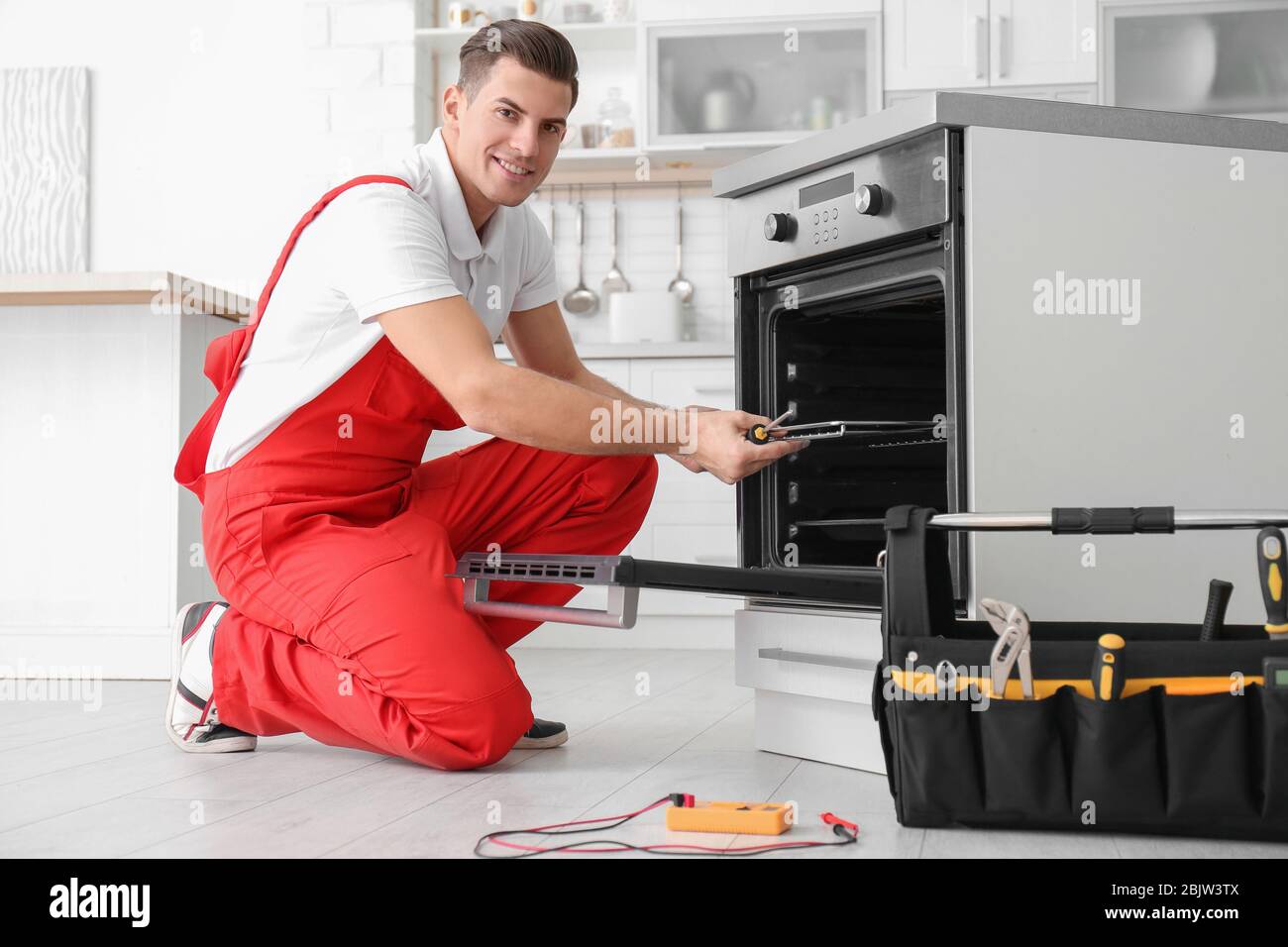 Young man repairing oven in kitchen Stock Photo