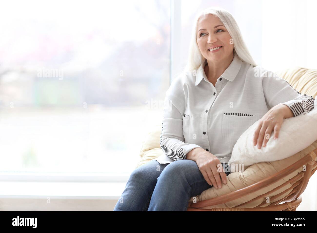 Portrait of beautiful mature woman sitting in armchair at home Stock ...