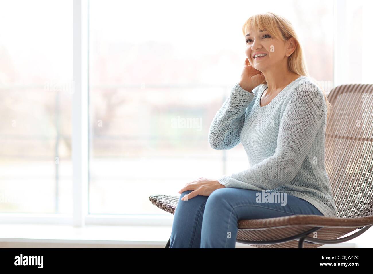 Portrait of beautiful mature woman sitting in armchair at home Stock ...