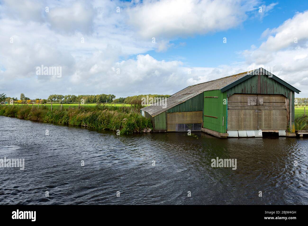 A roughly constructed green corrugated iron boat house on the little ringsloot, in Warmond in the Netherlands. Stock Photo