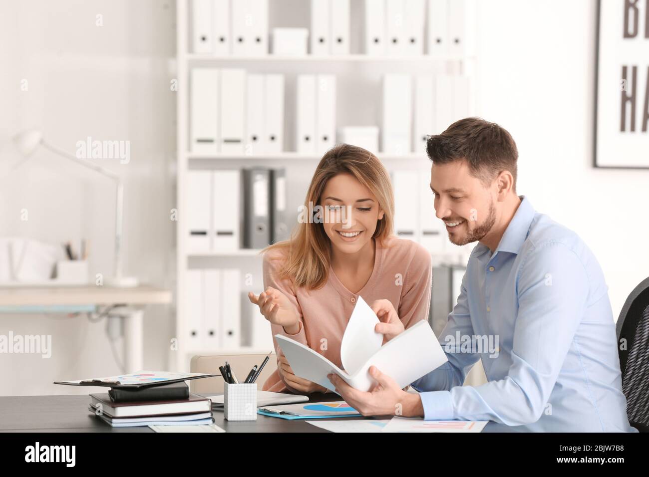 Businessman consulting young woman in office Stock Photo - Alamy