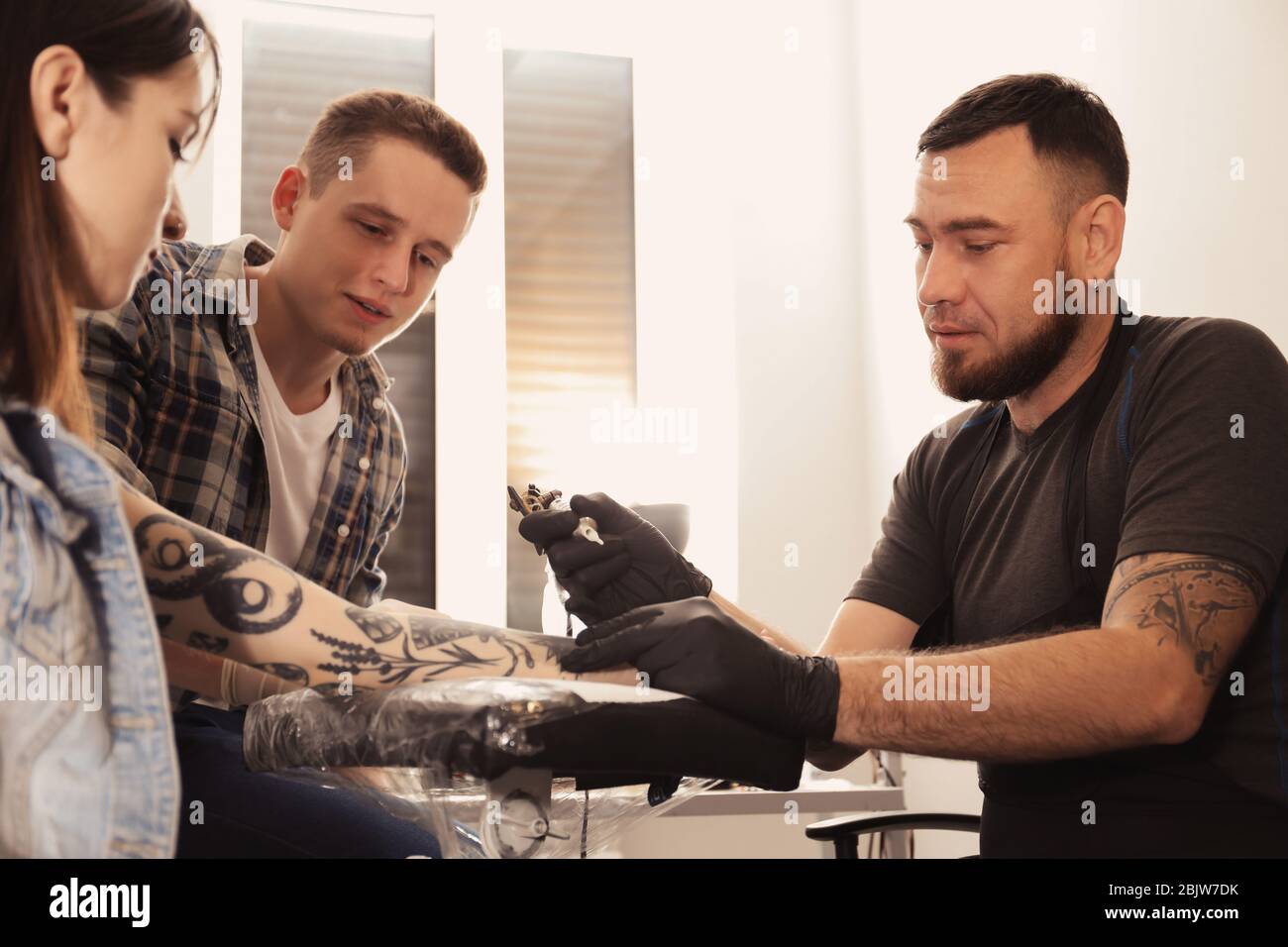 Professional tattoo master teaching young specialist in salon