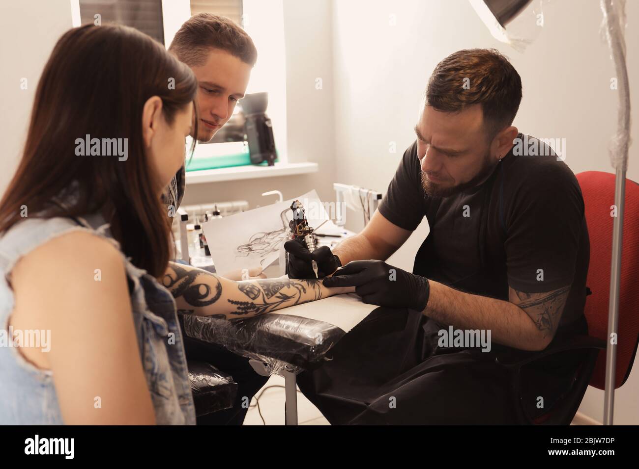 Professional tattoo master teaching young specialist in salon