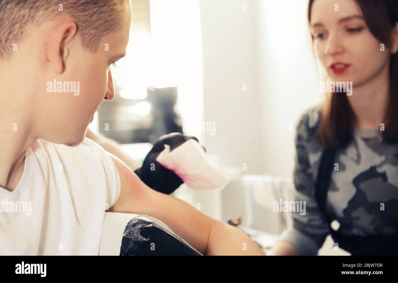 Professional tattoo master teaching young specialist in salon