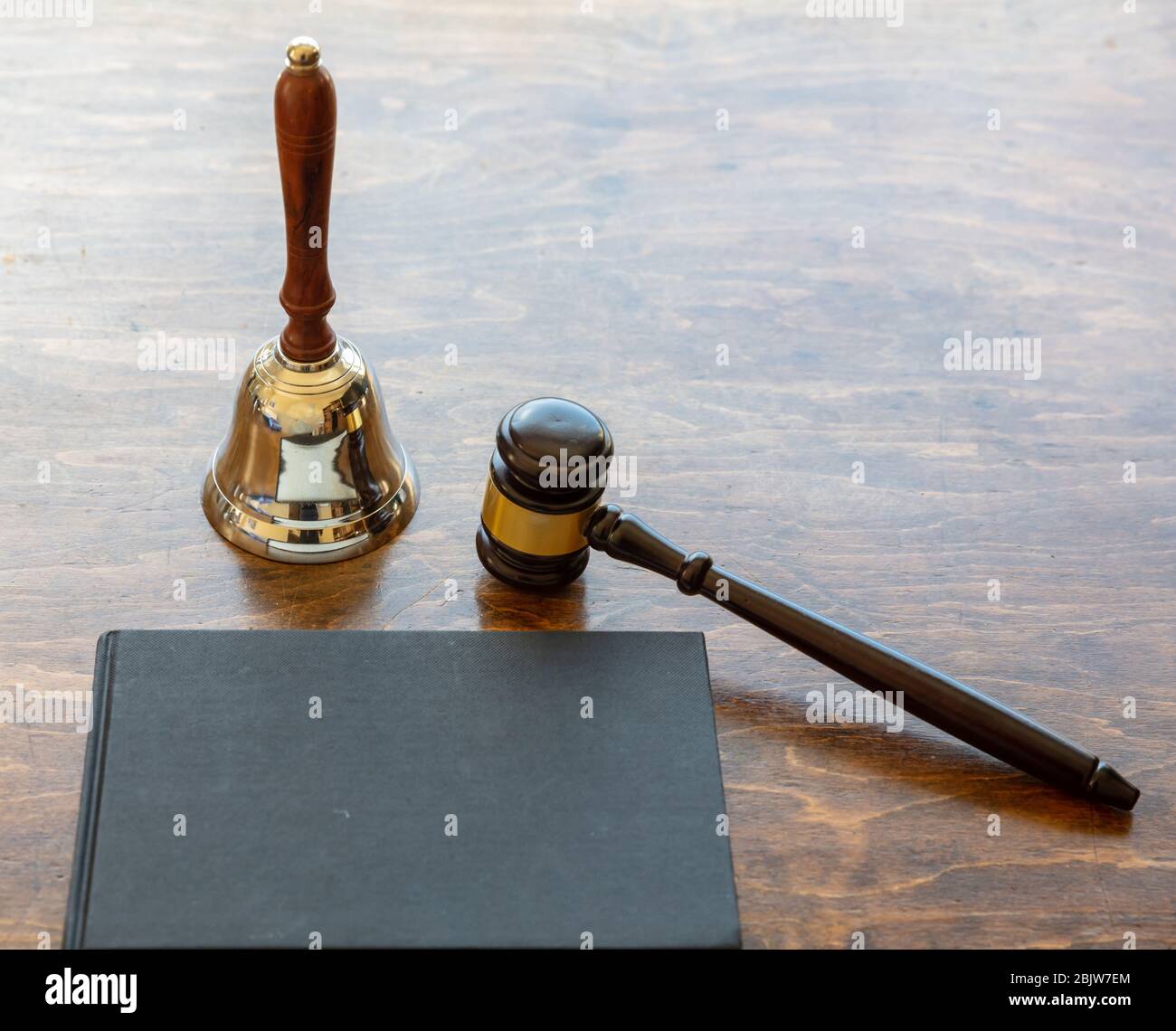 Law theme. Judge gavel and bell, a black blank legal book on wooden desk background, copy space. Auction, court table Stock Photo