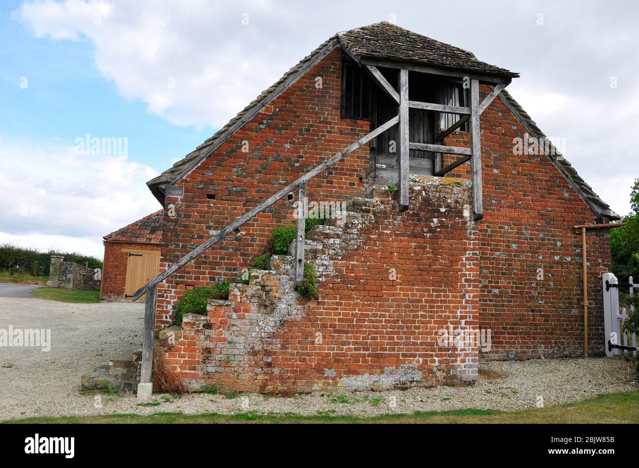Small brick built barn under a stone tiled roof with outside stairs to a loft. In the yard of the Great Coxwell Tithe Barn near Farringdon in Oxfordsh Stock Photo