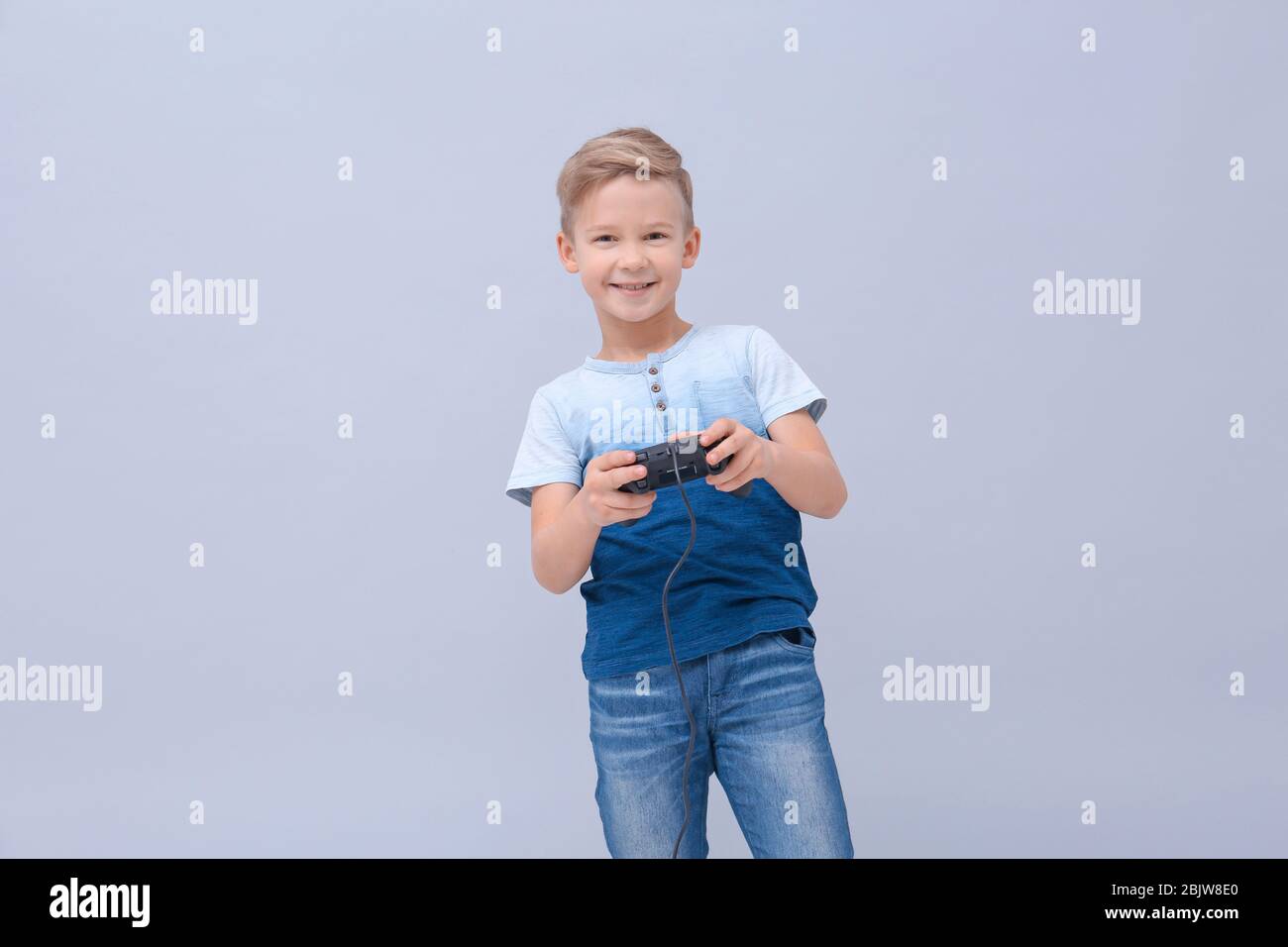 Cute boy with video game controller on color background Stock Photo - Alamy