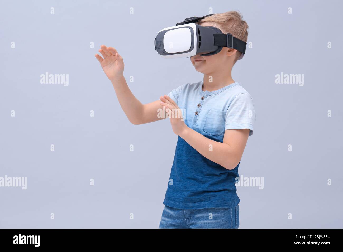 Cute boy with virtual reality headset on color background Stock Photo