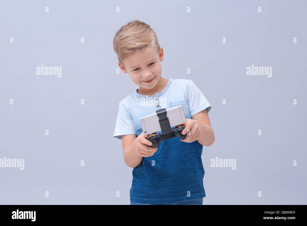 Cute boy with video game controller for smartphone on color background ...