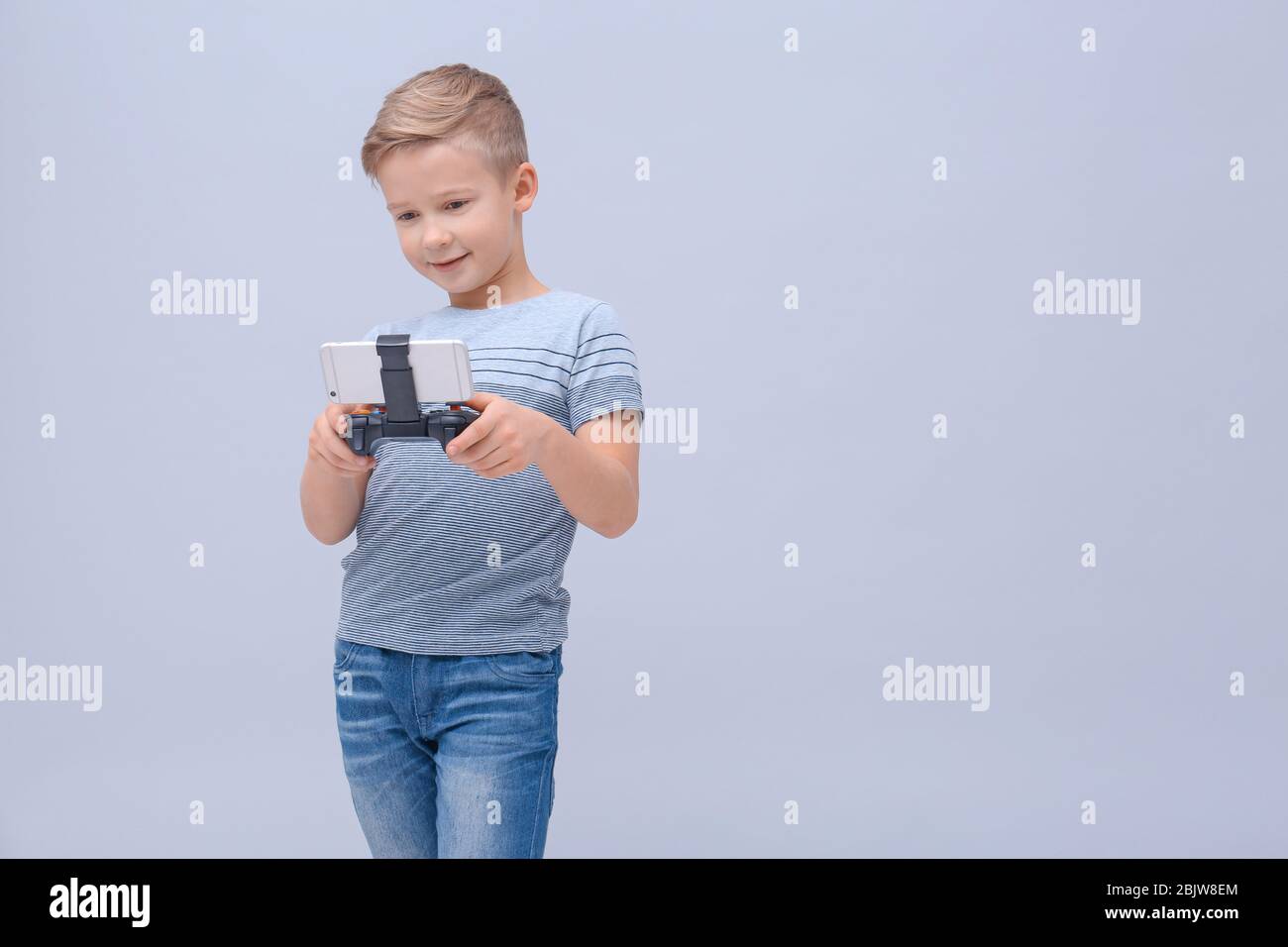 Cute boy with video game controller for smartphone on color background ...