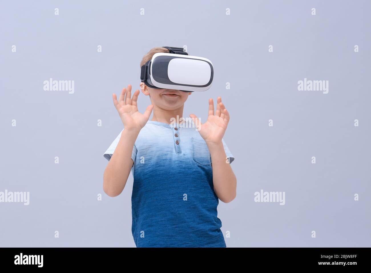 Cute boy with virtual reality headset on color background Stock Photo