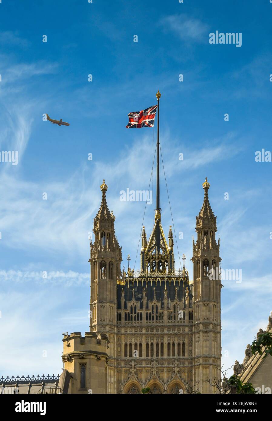 LONDON, ENGLAND - JUNE 2018: The Victoria Tower in the Palace of Westminster with the Union Jack flag flying and a passing jet Stock Photo