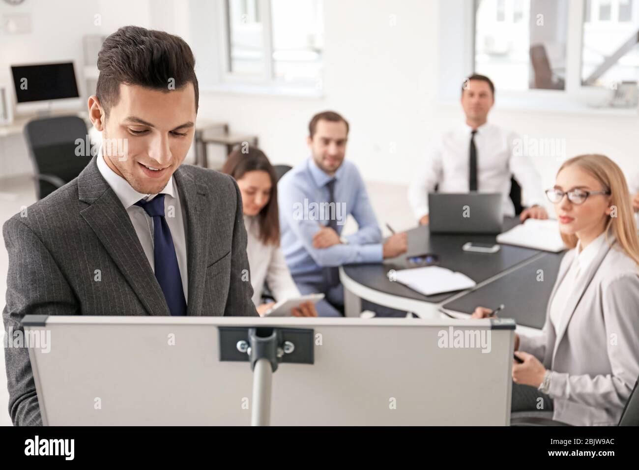 Business trainer giving presentation to group of people at management ...