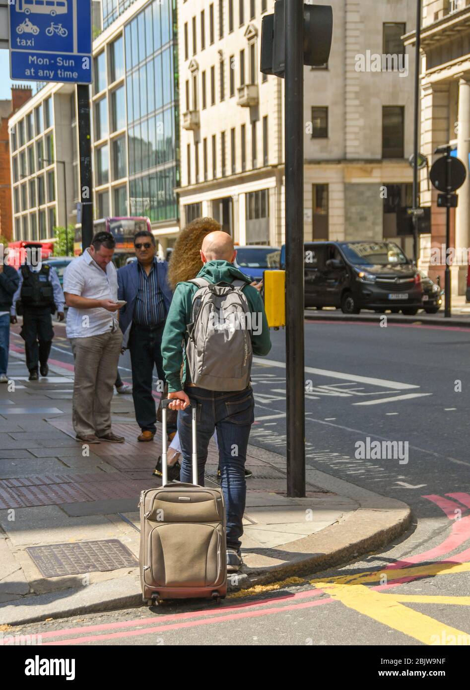 LONDON, ENGLAND - JULY 2018: Person walking down a street in central London pulling a suitcase Stock Photo