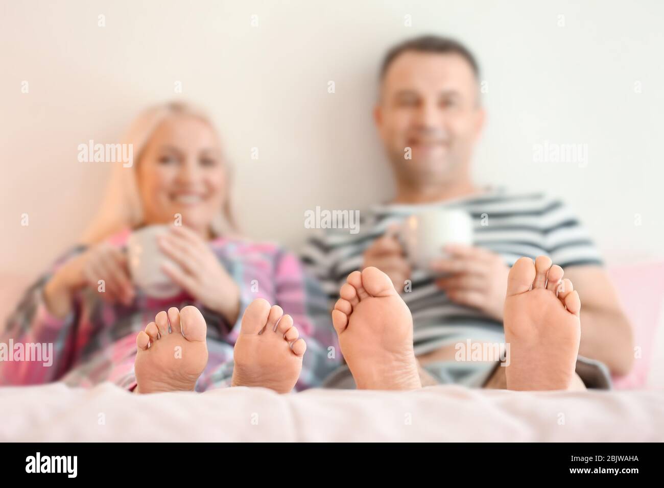 Senior couple drinking coffee on bed together Stock Photo