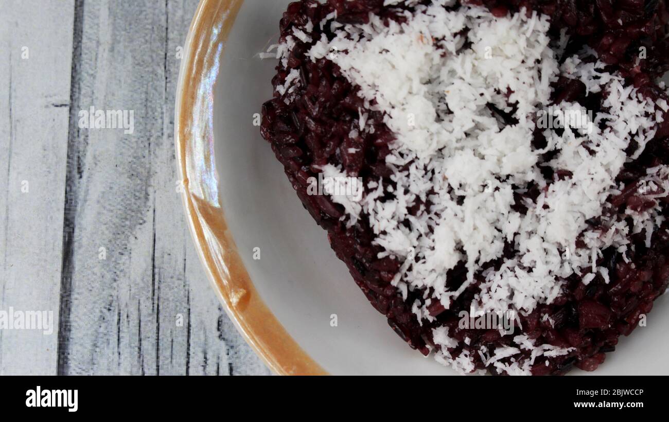 Black sticky rice or Ketan Hitam (Indonesian Name) with grated coconut, very delicious and sweet Stock Photo
