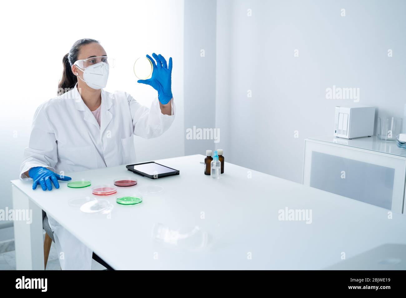 Young female researcher or Scientist examining solution in petri dish at a laboratory. The researcher is analyzing the medicine related innovation. Bi Stock Photo