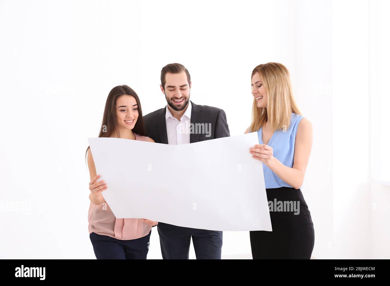 Real estate agent with trainee showing plan of apartment to client