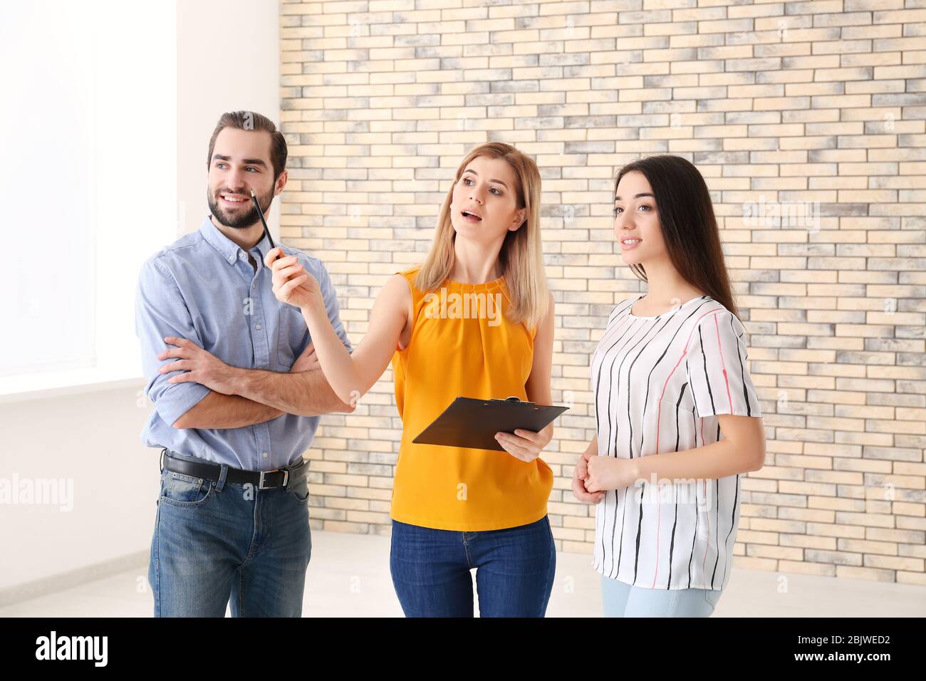 Real estate agent with trainee and client in empty apartment Stock