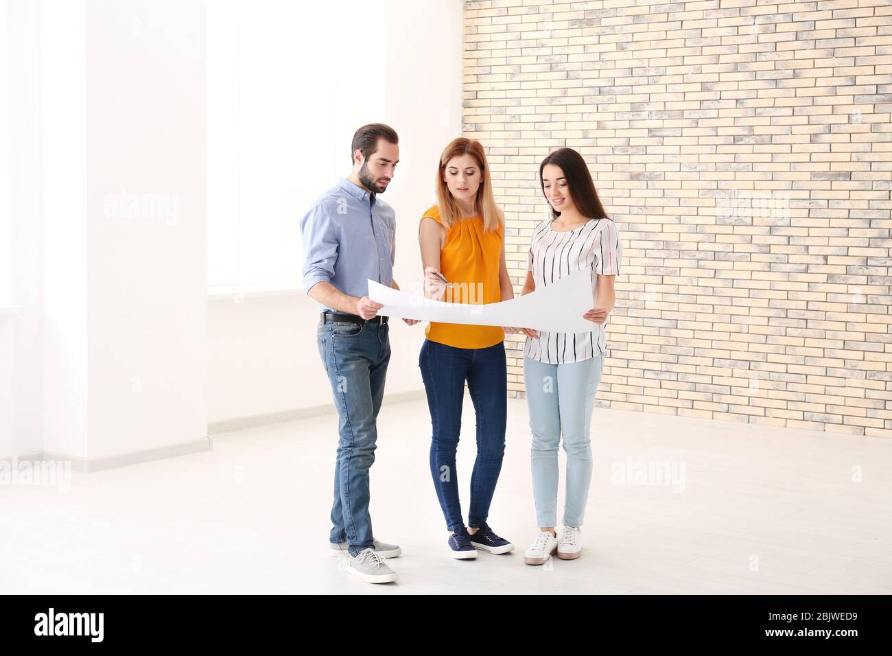 Real estate agent with trainee showing plan of apartment to client
