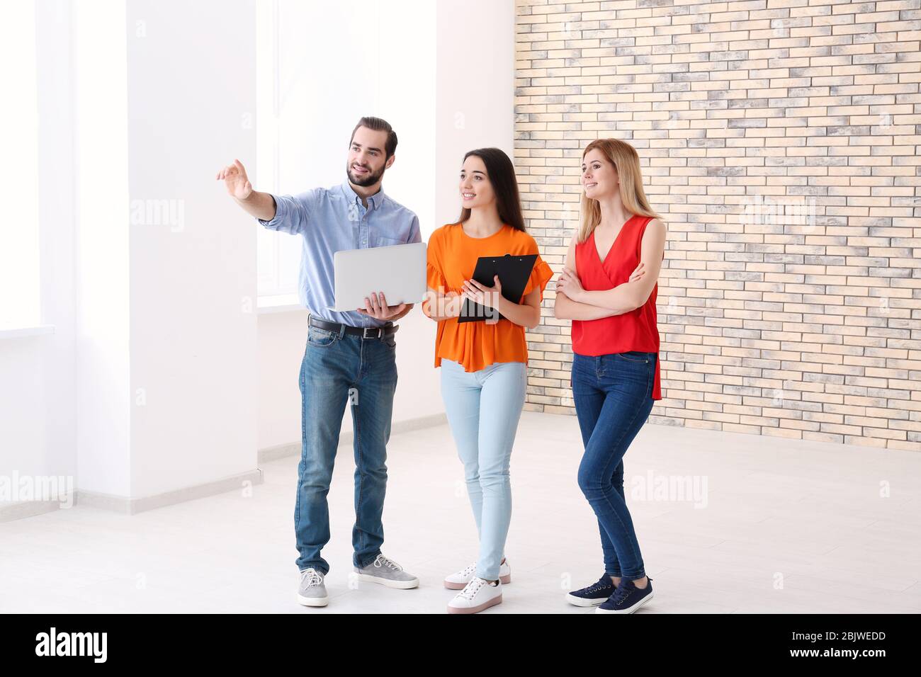 Real estate agent with trainee showing apartment to client Stock Photo