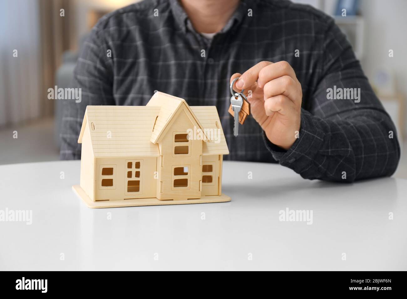Man holding key near house model, closeup Stock Photo - Alamy