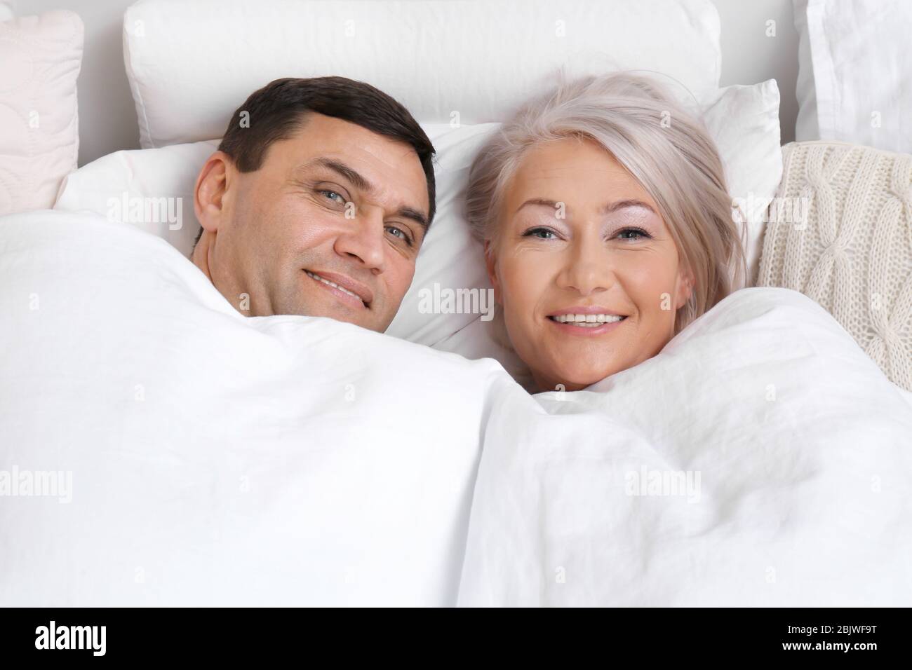 Mature couple under blanket in comfortable bed Stock Photo Alamy