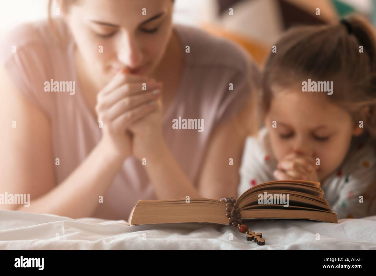 Religious Christian girl and her mother praying over Bible indoors ...