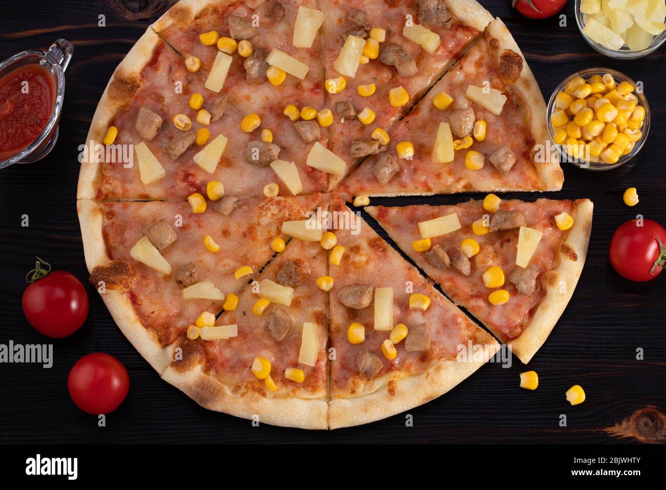 Pizza with chicken, pineapple and corn on dark background. Stock Photo