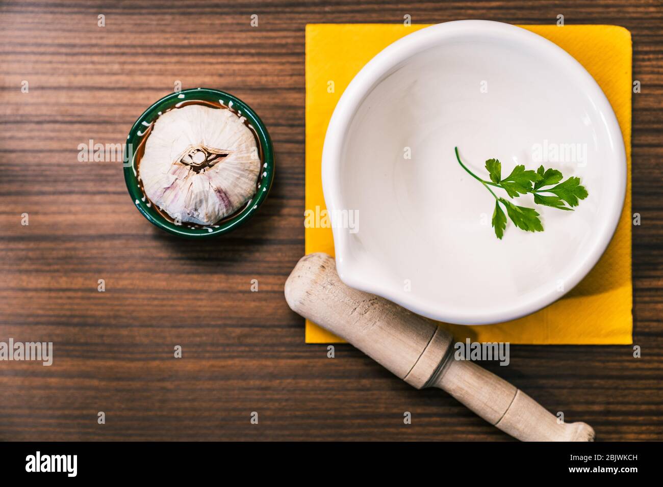 Preparing a recipe to make aioli in a traditional and homemade way. Ingredients and utensils to prepare garlic oil. Garlic head, parsley leaf and a mo Stock Photo