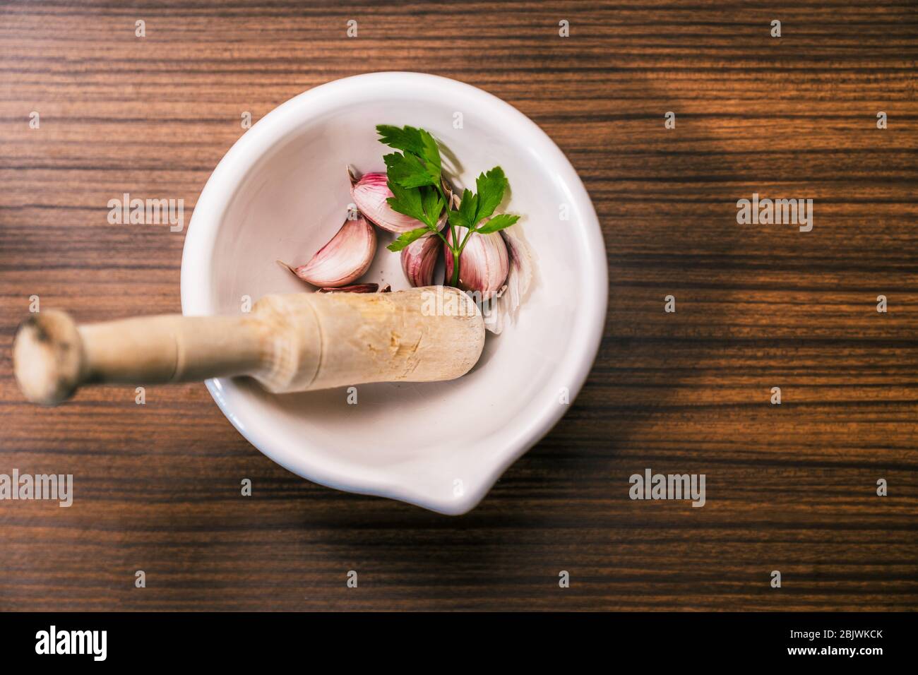 Preparing a recipe to make aioli in a traditional and homemade way. Ingredients and utensils to prepare garlic oil. Different garlic cloves, parsley l Stock Photo