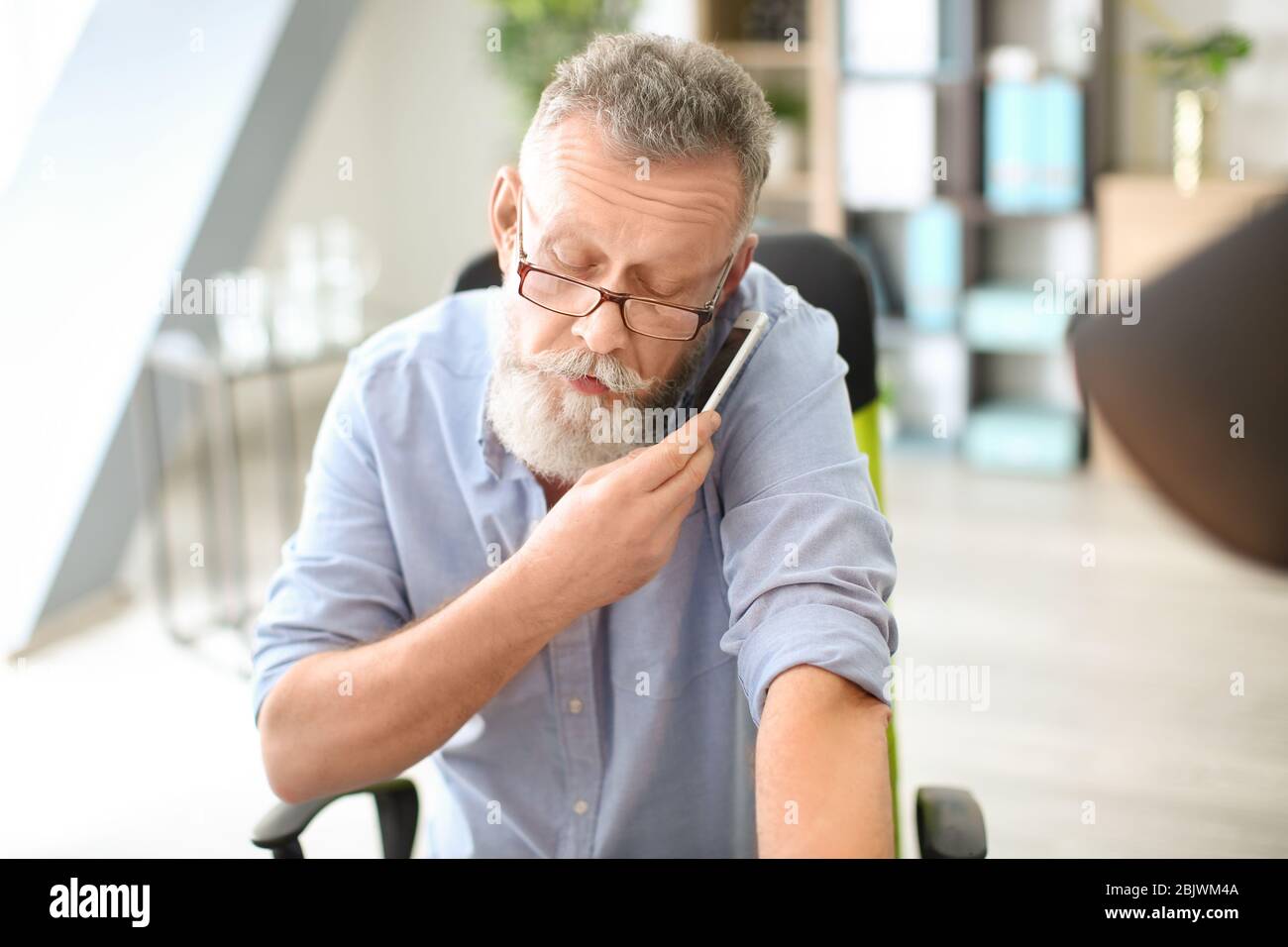 Senior man talking on mobile phone while working in office Stock Photo