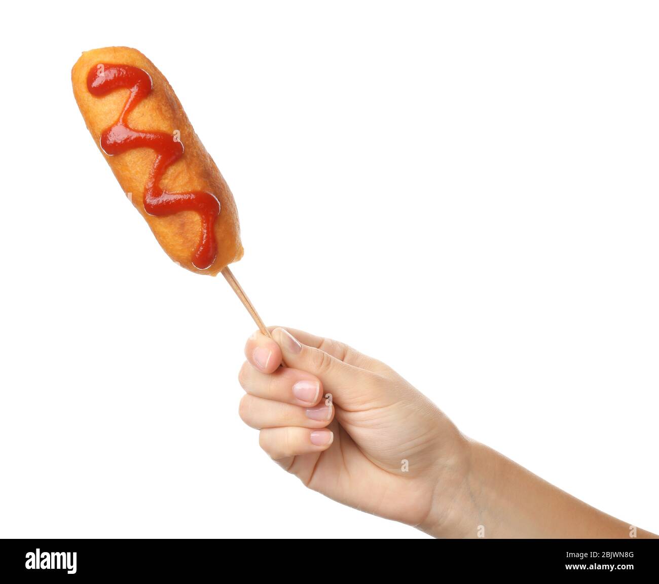 Woman holding tasty corn dog with ketchup on white background Stock Photo